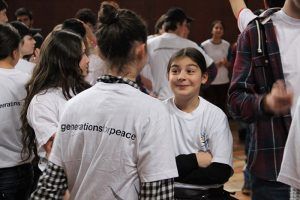 Young teenagers wearing Generations For Peace t-shirts talking and smiling