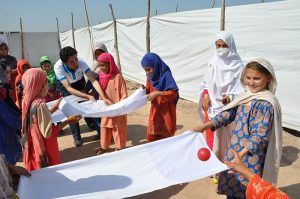 Pakistan, young girls playing a game where they roll a ball on stretched strips of white fabric