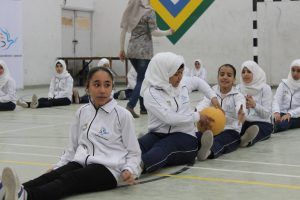 Young girls sitting on the floor passing each other a ball